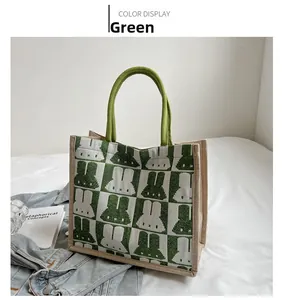 Detail of green and beige checkered knit tote bag with rabbit patterns on a bed