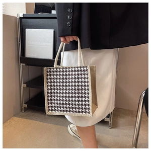 Dettaglio della borsa tote in lino pied-de-poule con manici in corda color crema indossata