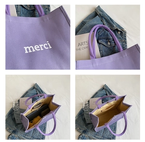 Detail view of purple canvas tote bag with merci print, interior lining, and large capacity