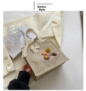 Detail view of linen tote bag featuring colorful plush flowers and a lace bow decoration