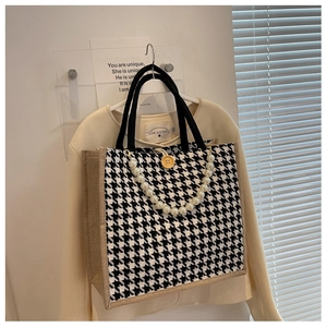 Detail of houndstooth patchwork tote bag with pearl charms and wooden button closure
