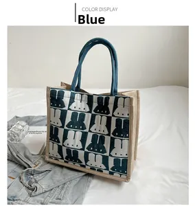 Blue and white checkered tote bag with rabbit patterns on a white bed