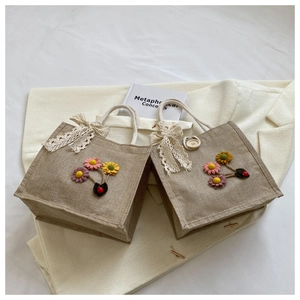 Close-up of handmade linen tote bags with fabric flowers and lace bow detail