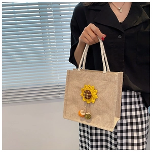Detail of beige burlap tote bag featuring 3D sunflower applique and white cotton rope handles