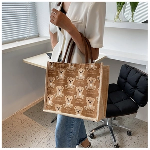 Detail of canvas tote bag with brown bear print and dark brown woven handles on a model