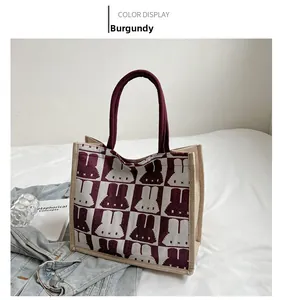 Detail view of wine red canvas tote bag with woven rabbit patterns and reinforced handles
