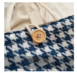 Detail of blue and white woven tote bag featuring a round wooden button and rope handle