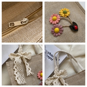 Detail of jute tote bag showing fabric flowers, lace bow, and metal zipper closure