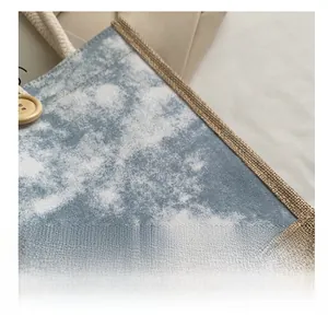 Dettaglio borsa di lino con motivo tie-dye blu, bottone in legno e manici in cotone bianco