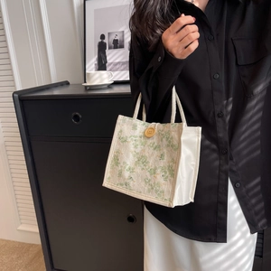 Dettaglio della mini borsa tote con pizzo bianco e ricami floreali verdi eleganti