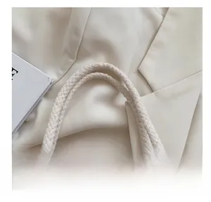 Detailed close-up of woven cotton rope handles on a minimalist linen handbag