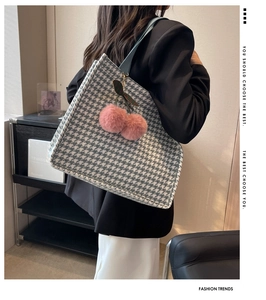 Detail of houndstooth tote bag with pink plush cherry charm and light blue strap
