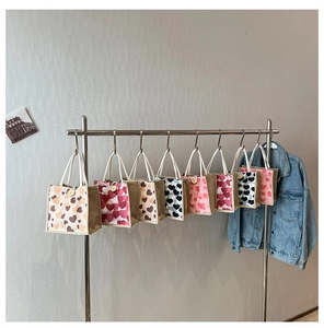 Hanging display of linen mini tote bags with heart patterns and wooden button closure