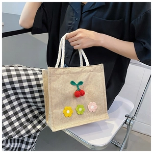 Detail of woven jute tote bag with handcrafted crochet cherry and floral patterns