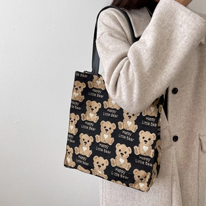Minimalist canvas tote bag with cartoon bear pattern shown on a shoulder of a model