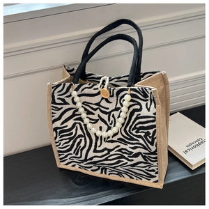 Detail of zebra pattern canvas tote with pearl chain and jute texture side panels