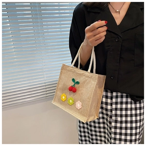 Detail of burlap tote bag featuring handmade crochet cherry and floral decorations