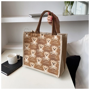 Detail of canvas tote bag featuring teddy bear print and brown rope handles for commuting