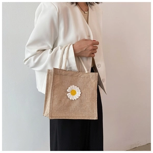 Detail of jute tote bag featuring a white daisy embroidery and woven cotton rope handles