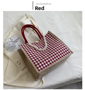 Detail of red houndstooth tote bag featuring pearl strap and circular handles