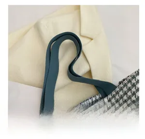 Detail of grey houndstooth fabric tote bag with dark green canvas straps and leaf charm