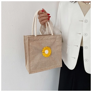 Close-up of small jute tote bag with yellow daisy embroidery and white woven handles