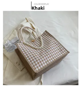 Detail of khaki houndstooth tote bag featuring woven texture and decorative pearl chain