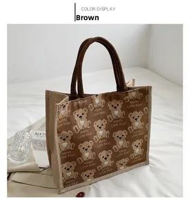Detailed close-up of brown canvas tote bag with cartoon bear patterns and braided handles