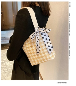 Detail of hand-woven herringbone canvas bag with white strap and polka dot silk scarf