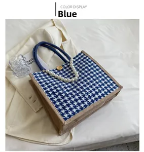 Detail of blue houndstooth tote bag with large pearl charm and decorative button