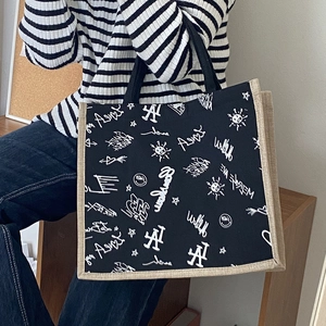 Graffiti canvas tote bag in black with LA print and khaki woven trim held by a model