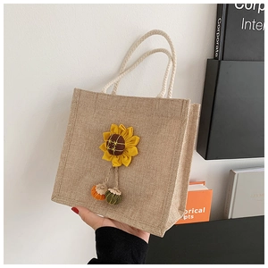 Close-up of mini jute tote bag featuring a 3D sunflower and woven pompom charms
