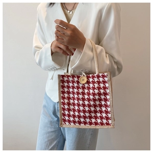 Detailed close-up of a red houndstooth linen handbag with cotton rope handles and wood button