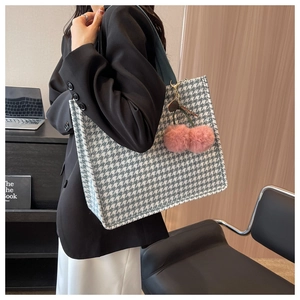 Detail of houndstooth tote bag featuring pink plush cherry charm and teal handles
