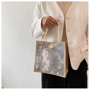 Dettaglio borsa tote in lino con motivo tie-dye, bottone in legno e manico in corda