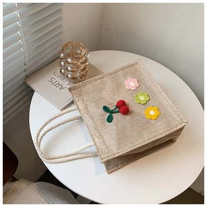 Detail of woven jute tote bag with crochet flower accents and soft cotton rope handles