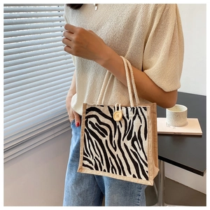 Close-up of zebra print linen tote bag featuring a vintage wooden button and woven handles
