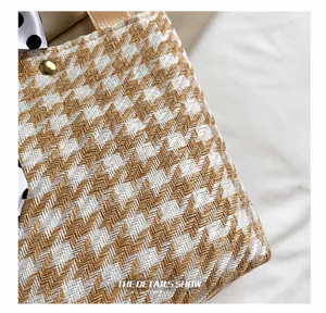 Close-up of houndstooth woven handbag featuring a gold rivet and polka dot silk scarf