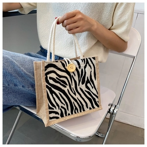 Detail of zebra pattern linen handbag with white rope handle and wooden button accent