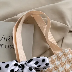 Detail of beige woven handbag with matching ribbon handle and polka dot silk bow decoration
