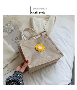 Detail of khaki jute handbag featuring yellow daisy embroidery and woven handles
