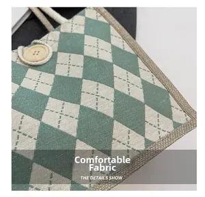 Close-up of green and white argyle canvas texture with a wooden button closure