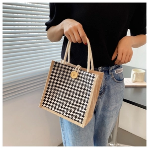 Close-up of linen handbag with black houndstooth pattern and wooden button closure