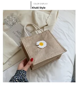 Detail view of khaki jute handbag with embroidered daisies and white rope handle