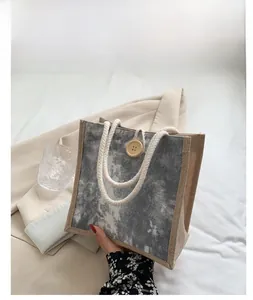 Dettaglio borsa in lino grigio marmorizzato con bottone in legno e manico in corda di cotone