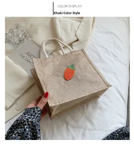 Detail of khaki jute handbag with carrot embroidery and woven handles