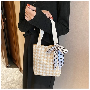 Detail of beige houndstooth tote bag with cream handles and elegant polka dot ribbon