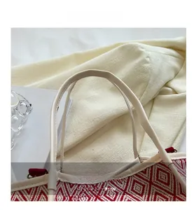 Close-up of the cream PU leather handle and red-white geometric woven pattern detail