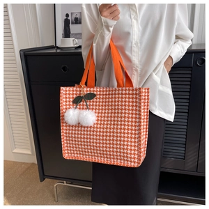 Close-up of orange houndstooth tote bag featuring a cute cherry plush pompom charm