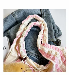 Detail of pink and white ruffled handle and yellow plush character on canvas bag